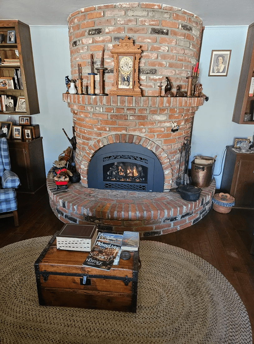 Brick fireplace with wooden chest in foreground.